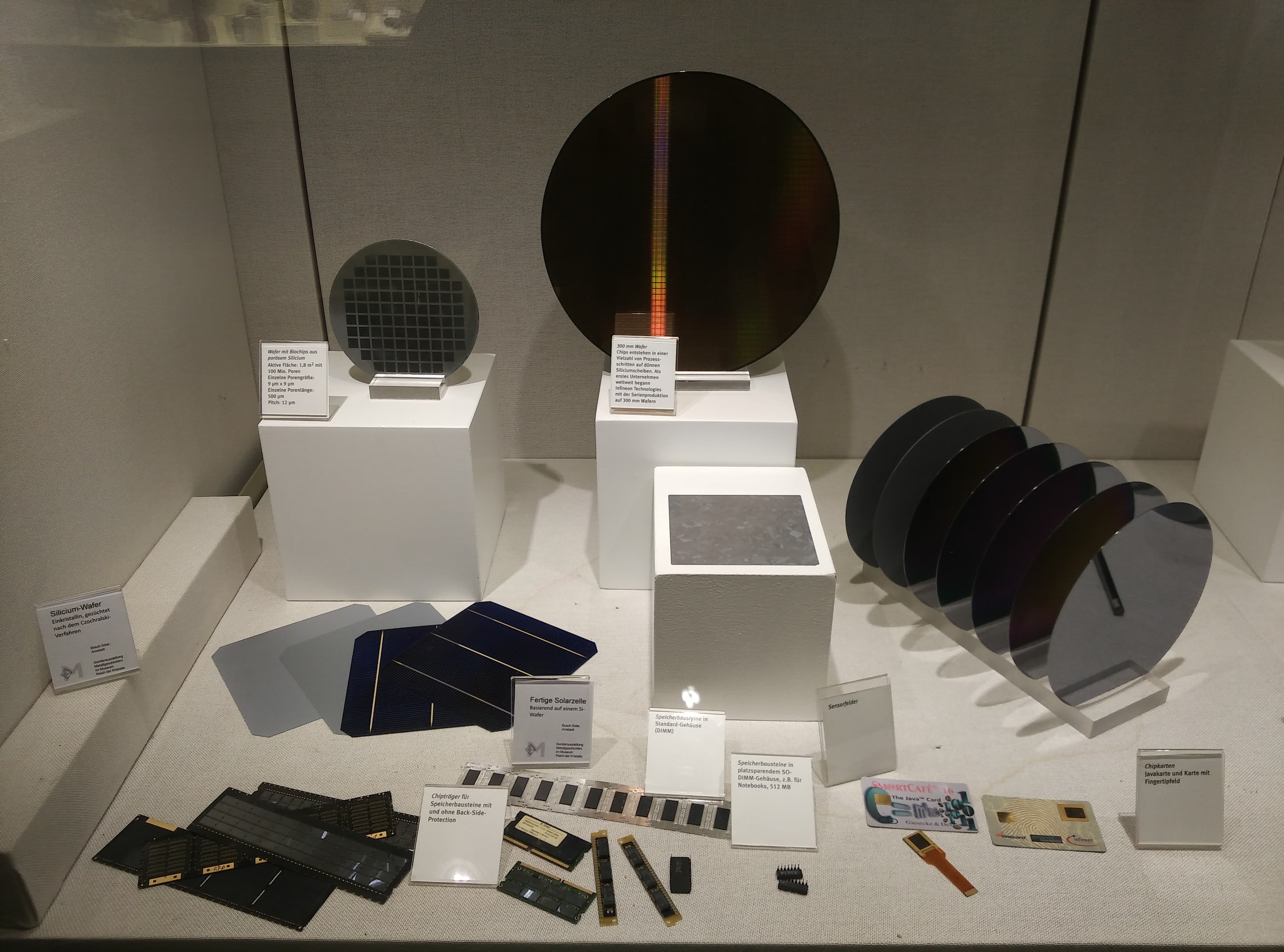 Silicon wafers and electronic products displayed together to show the relationship between semiconductor material and finished electronics.