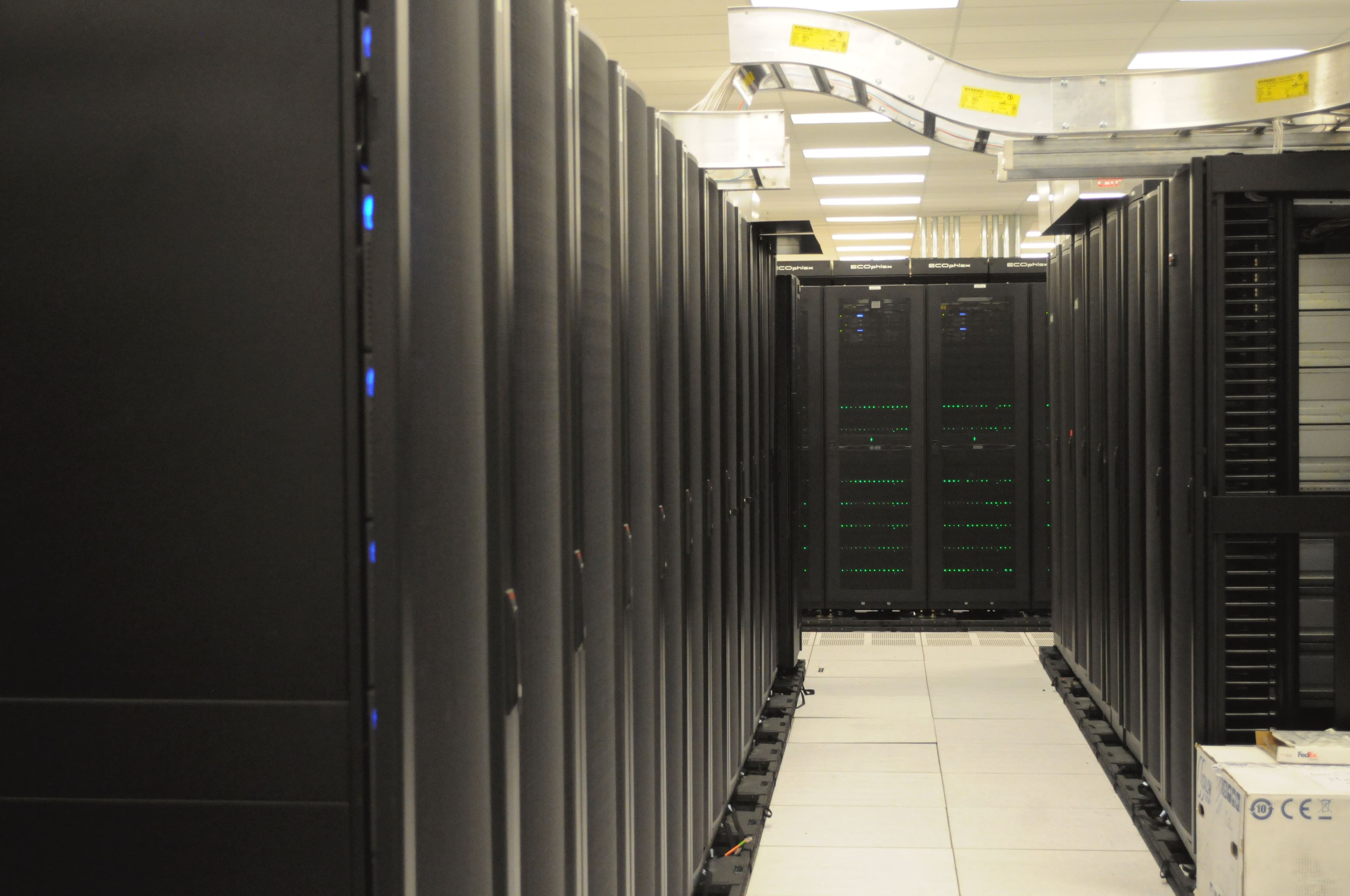 Rows of server racks and overhead cabling inside the NERSC data center.