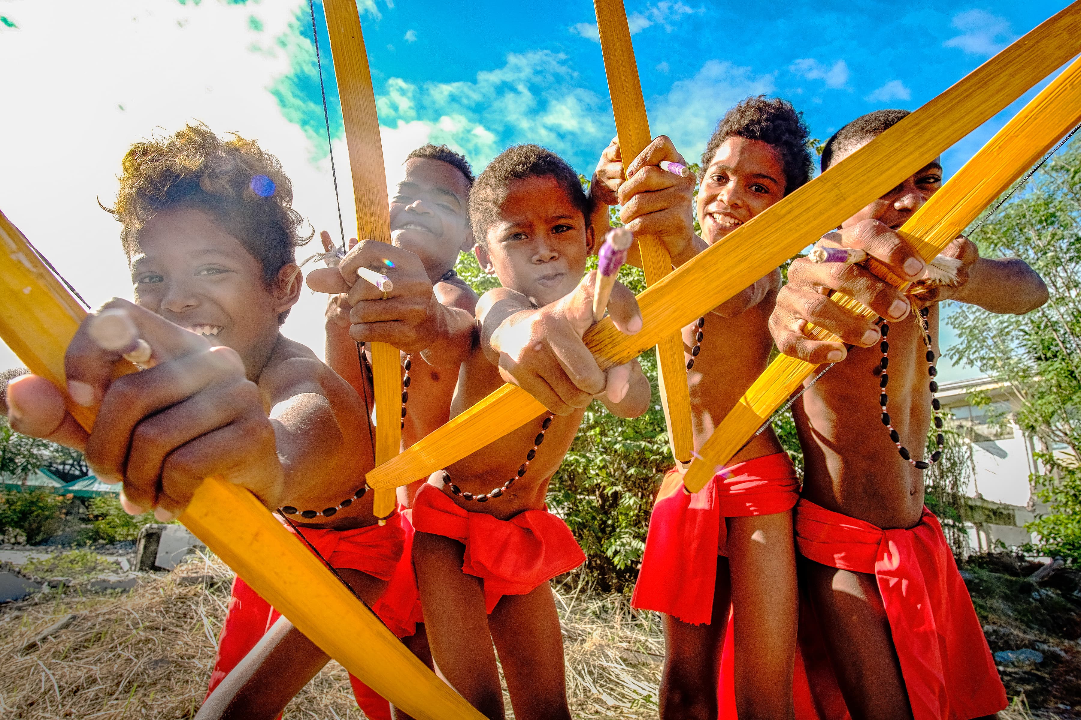 Aeta children in the Philippines wearing traditional clothing and holding bows and arrows.